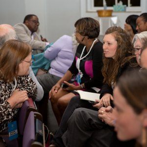 A crowd of attendees at a social justic event chatting before the seminar starts.