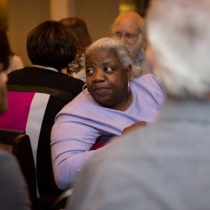 A woman looking behind her to listen to someone speaking at a church-hosted social justice event.