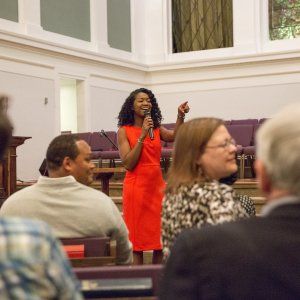 Our founder Kahlida smiling and pointing during a speech at a church-hosted event.