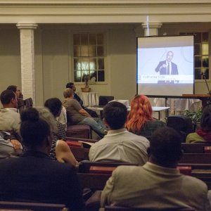 Reconcilers sitting in pews, watching a slideshow presentation about racial reconciliation.