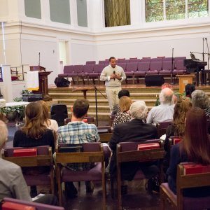 A crowd listening intently to a speech about fighting racism at a church-hosted event.