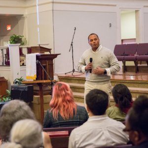 A man giving a speech about fighting racism in communities while attendees listen in a church.