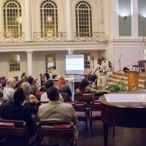 Attendees of a racial reconciliation event sit inside a church, listening to a presentation.