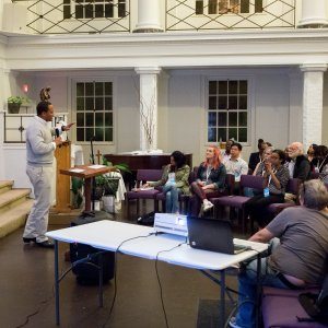 A slide project and laptop on a table. A man giving a speech about fighting racism to church goers in New Orleans.