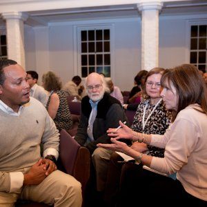 Room full of people of different races talking and getting to know each other.