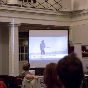 People watching a slideshow about the complications of racism at a church-hosted event.