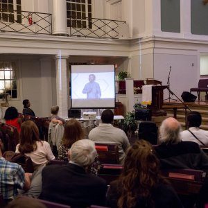 People watching a slideshow about racism during a church-hosted event.