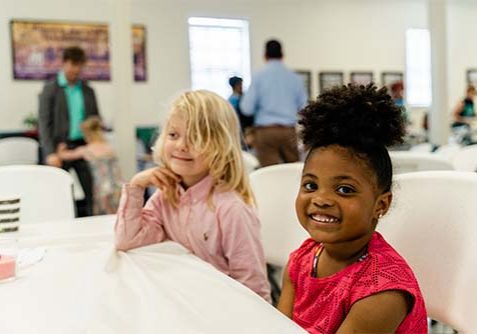 two young girls smiling at a table